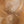 The painting “Warmth Whirlwind” is a textured abstraction in golden-copper tones.
